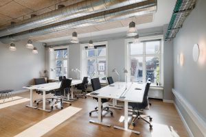 Stort 10-personers kontor på ordnung+ Bredgade med hæve/sænke-skriveborde, ergonomiske kontorstole og store vinduer med lysindfald.